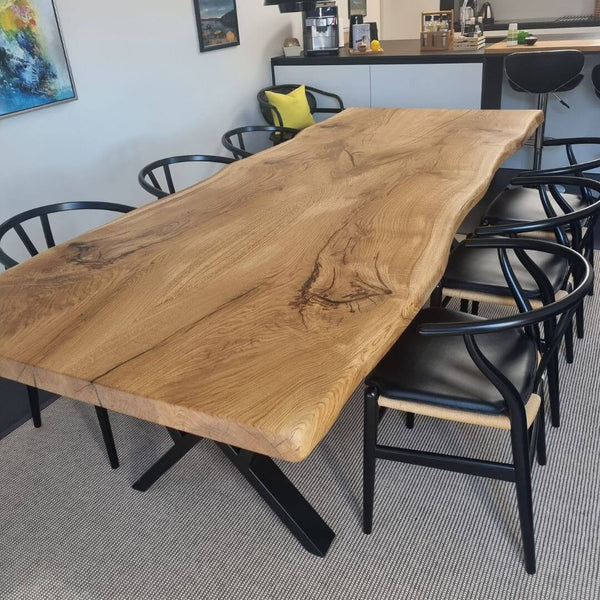 Plankebord i egetræ med naturkant og elegante sorte spisebordsstole