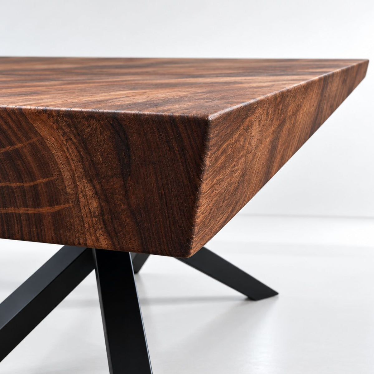Nærbillede af 5 cm tyk bordplade i massiv valnød med elegant skrå vinkelkant og sort metalstel.