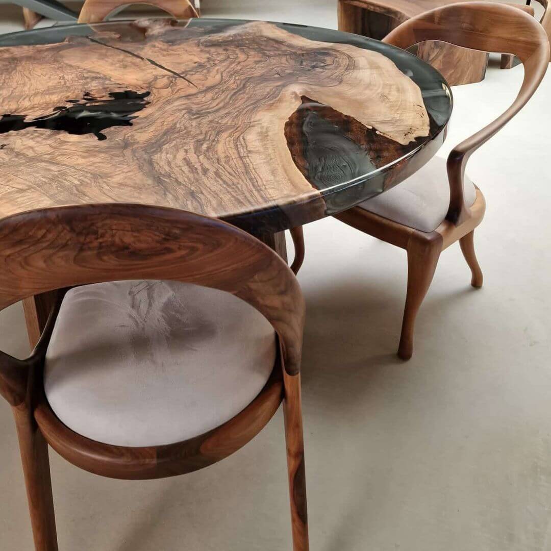 Rundt plankebord i valnød med grå epoxy og træben i showroom.