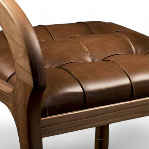 Nærbillede af spisebordsstol i valnød med brunt lædersæde og træarmlæn.