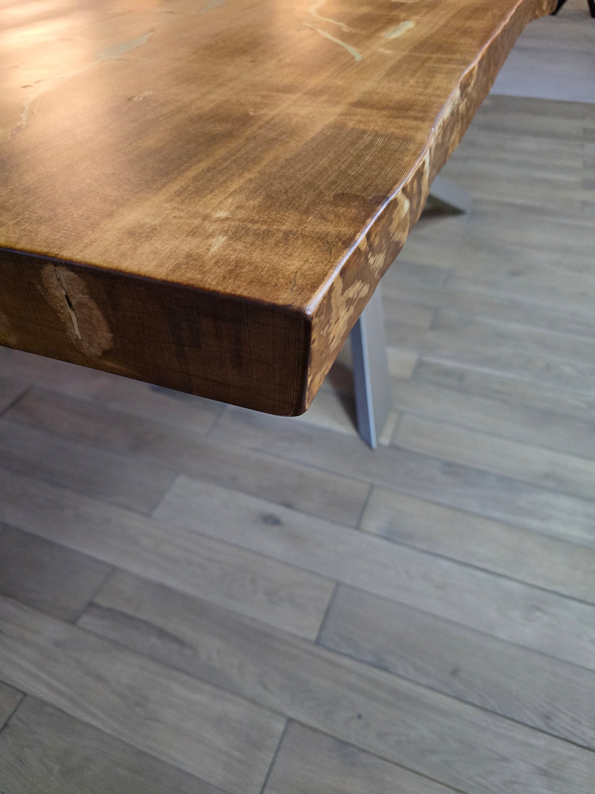 Plankebord i fyrretræ med naturkant og karakterfulde årer, monteret på bordben i sort metal