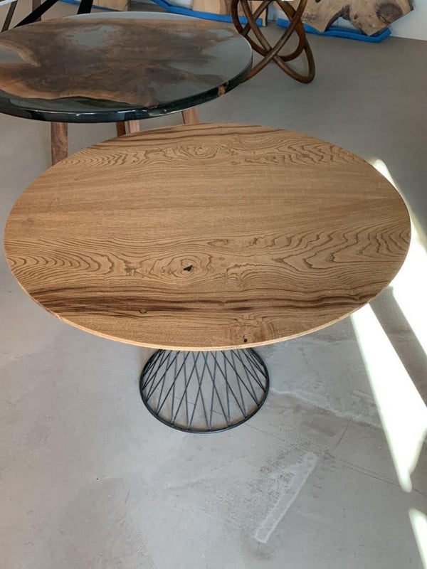 Rundt spisebord i kastanjetræ med sort metalstel på showroom-gulv.